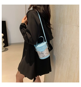 Detail of light blue leather bucket bag with white lace embroidery on a model