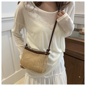 Detail of a minimalist straw crossbody bag with contrast PU leather strap and trim