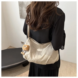 Detail of beige tote bag with natural texture, cookie plush charm and fashion emblem