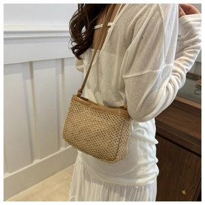 Detail of hand-woven straw crossbody bag with delicate hollow texture and slim shoulder strap