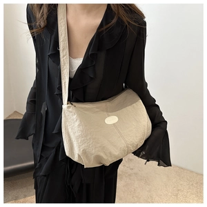 Detailed close-up of beige shoulder bag with fashion metallic logo and soft texture