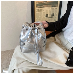 Detail view of silver bucket bag featuring heart patches and drawstring closure