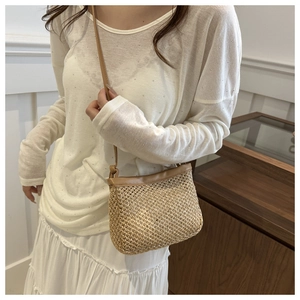 Detail of hand-woven straw bag with tan leather trim and textures on a model
