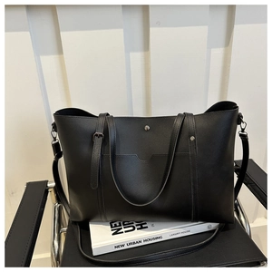Detail view of a black soft leather tote bag with a functional front pocket and metal stud