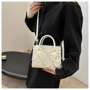 Detail of white canvas tote with tassel diamond pattern and leather top handles