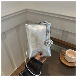 Gros plan du sac de téléphone argenté avec texture froissée et nœuds décoratifs