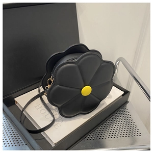 Detail of a black daisy shaped shoulder bag with yellow button core on a white book gift box