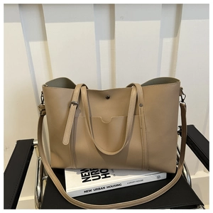 Detail of soft beige PU leather tote bag with functional outer pocket on black armchair