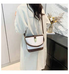 Modern woven texture bucket bag with contrast brown strap worn in a minimalist interior
