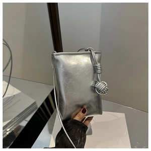 Détail macro du sac de téléphone argenté métallisé avec texture froissée et bandoulière