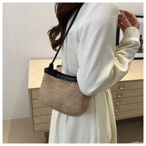 Detail of straw woven bucket bag with black leather trim and knot strap on a model