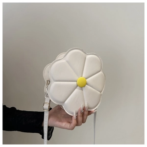 Detailed macro view of a white flower-shaped shoulder bag with a yellow button center