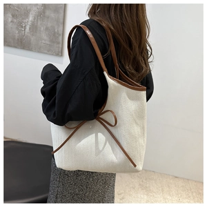Detail view of large canvas tote bag with brown leather straps and bow tie decoration