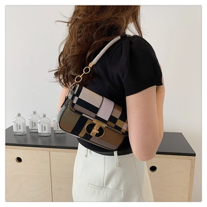 Détail d'un sac à bandoulière patchwork coloré avec un fermoir en T doré porté par un modèle