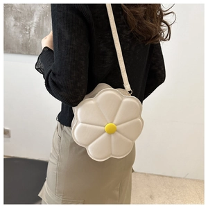 Detail of a white daisy shaped crossbody bag with yellow center and quilted flower petals