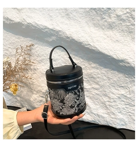 Detail of black cylindrical bucket bag with floral embroidery and silver hardware zipper