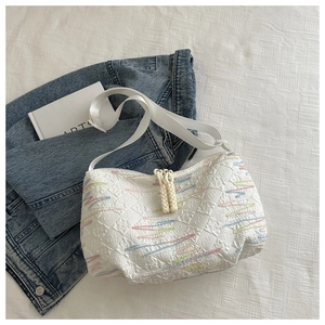Detailed macro of embroidered wavy lines and embossed texture on the white canvas bag