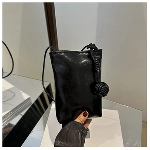 Détail de la pochette de téléphone noire brillante avec bandoulière à nœud sphérique unique