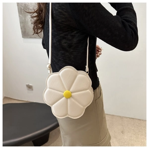 Detail of white 3D flower crossbody bag with yellow center on a black outfit