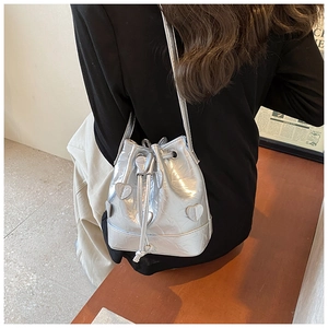 Close-up of silver drawstring bucket bag with pleated texture and heart-shaped leather patches