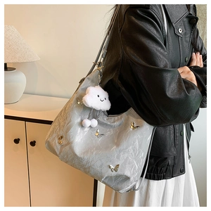Détail du sac cabas plissé argenté avec papillons et pendentif nuage en peluche doux