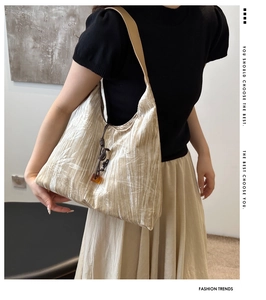 Détail d'un sac porté épaule beige avec imprimé bambou et charm décoratif en perle d'ambre