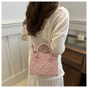 Detail view of pink frayed denim texture on a large capacity crossbody bag with strap