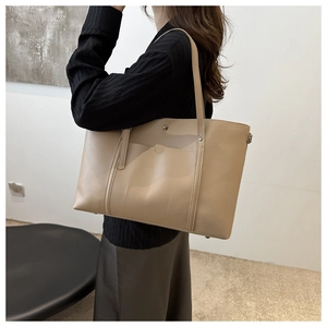 Detail view of a beige soft leather tote bag showing front pocket and reinforced handles