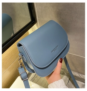 Detail of blue saddle crossbody bag with Fashion Trend text and adjustable strap