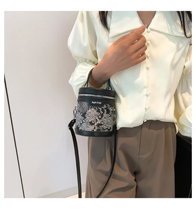Detail view of the elegant floral embroidery on a black bucket bag with jingpin print