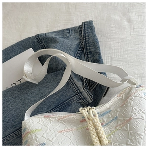 Macro detail of white waffle-textured canvas bag with colorful embroidered stripes