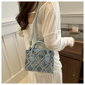 Detail of light blue denim crossbody bag with vintage quilted pattern and frayed edges