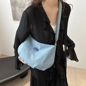 Minimalist light blue nylon tote bag with pleated texture and adjustable strap worn by model