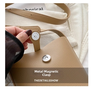Close-up of silver magnetic snap button on brown lychee grain leather crossbody bag
