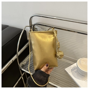 Détail du sac bandoulière doré métallisé avec nœuds décoratifs et texture froissée