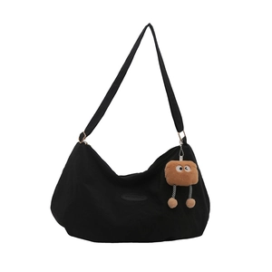 Black canvas tote bag with a brown plush monster charm and adjustable shoulder strap