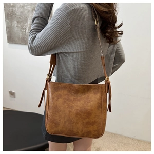 Detailed close-up of brown vintage leather bucket bag texture with adjustable strap