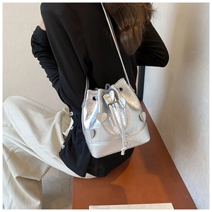 Detail of silver drawstring bucket bag with pleated texture and 3D heart appliqué