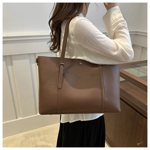 Detail of soft brown faux leather tote with adjustable straps and front pocket