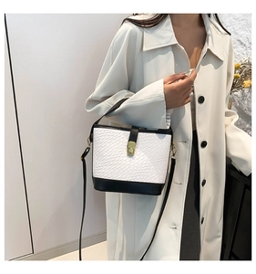 Detail of black and white bucket bag with crocodile texture and gold square lock