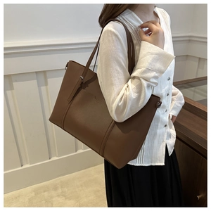 Close-up of brown grain leather tote bag with decorative stitching and shoulder strap