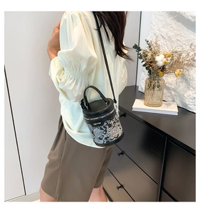 Detail of black cylinder bucket bag with white floral print and adjustable strap