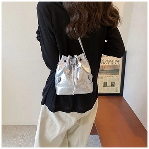 Detailed view of silver drawstring bucket bag with pleated texture and heart appliqués