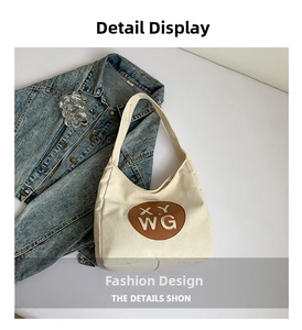 Detail of cream canvas tote bag featuring brown oval leather patch with white lettering