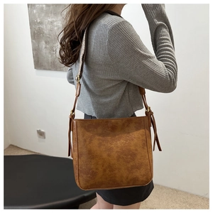 Detailed macro view of the caramel brown vintage bucket bag with glossy leather texture