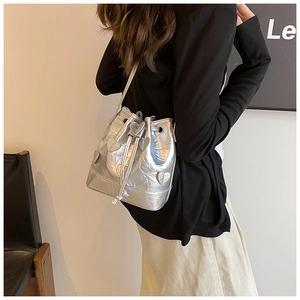 Detail of silver metallic bucket bag featuring 3D heart appliques and drawstring closure
