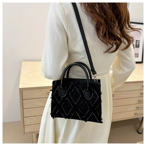 Close-up of black quilted tote bag featuring frayed edges and detailed tassel textures