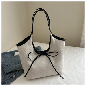 Détail du sac cabas en lin à chevrons avec bordure en cuir noir et nœud décoratif chic