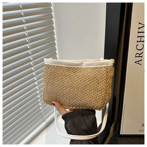 Detail of hand-held straw crossbody bag with white leather straps and woven texture