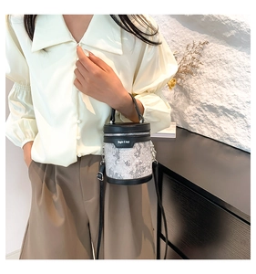 Detail of grey embroidered bucket bag with black leather trim and long shoulder strap